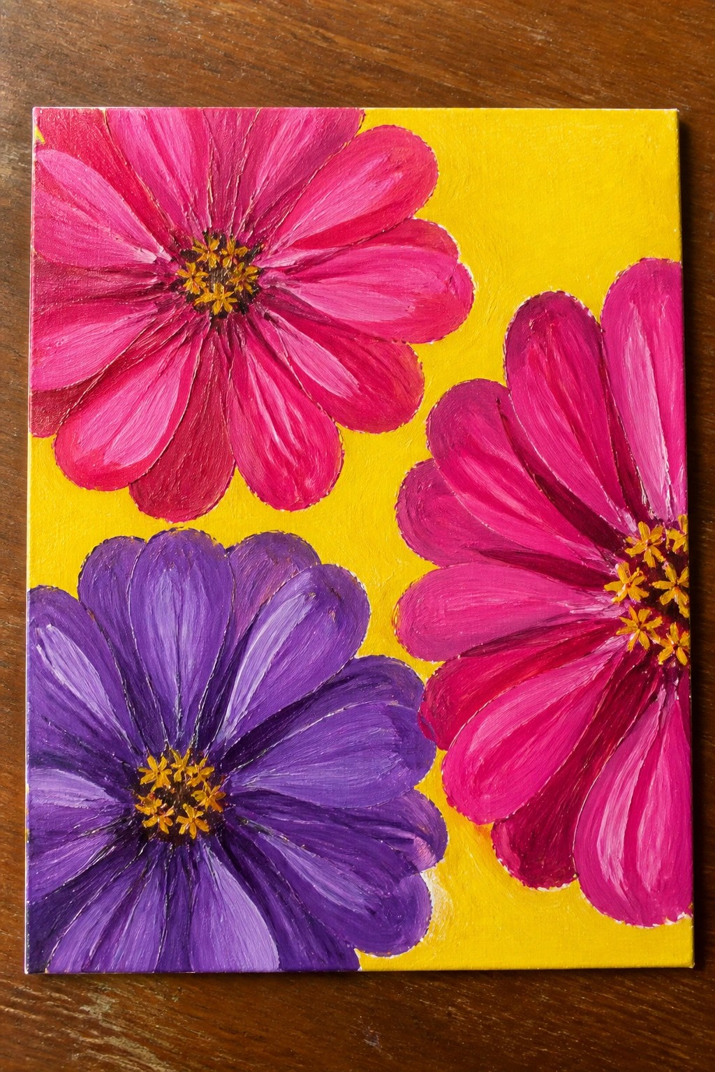 Vibrant painting of three pink and purple flowers on bright yellow background