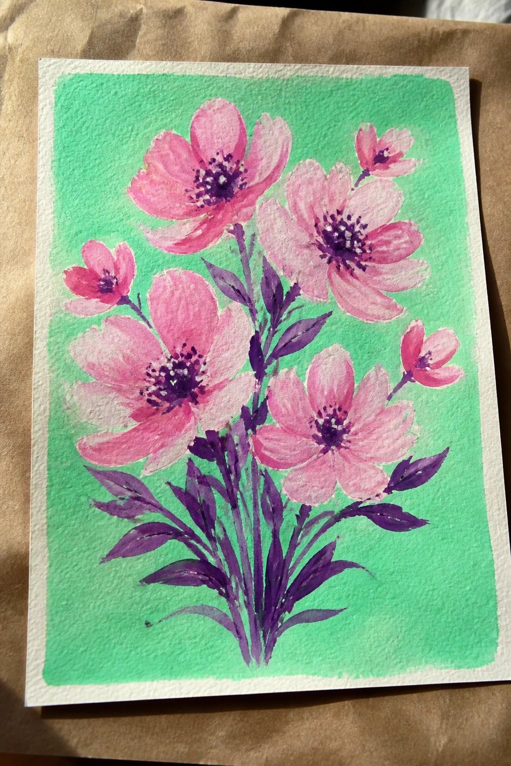 Watercolor of pink flowers with purple centers and stems on green background