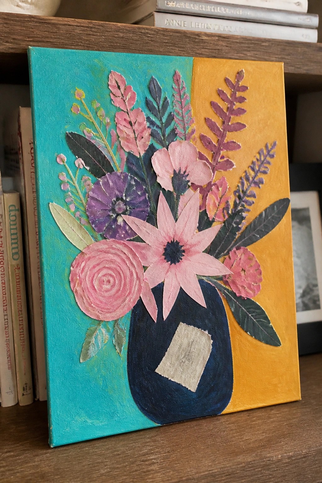 Mixed-media pink and purple flowers in a blue vase on split teal-yellow canvas.