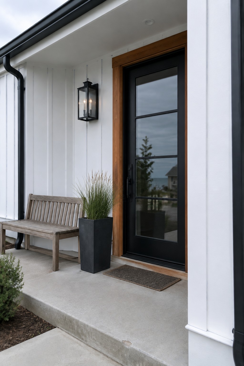 White vertical siding on a house exterior beside a black door with wood trim.