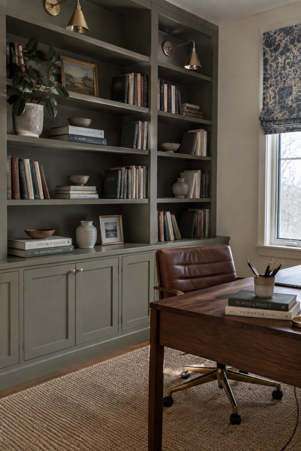 Built-in bookshelves and cabinets painted in a muted greige with green undertones in a home office.