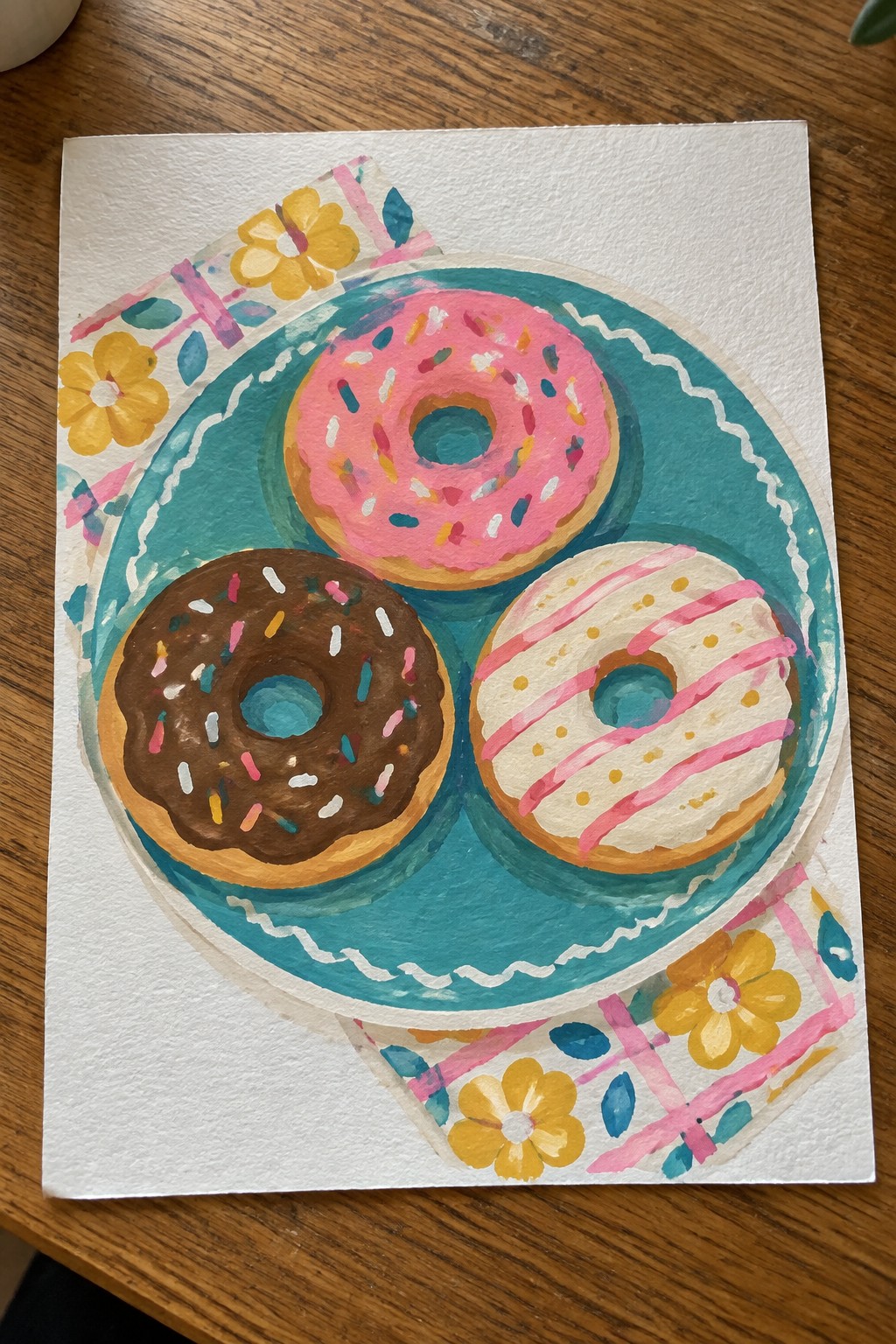 Watercolor painting of three sprinkled donuts on teal plate with floral cloth