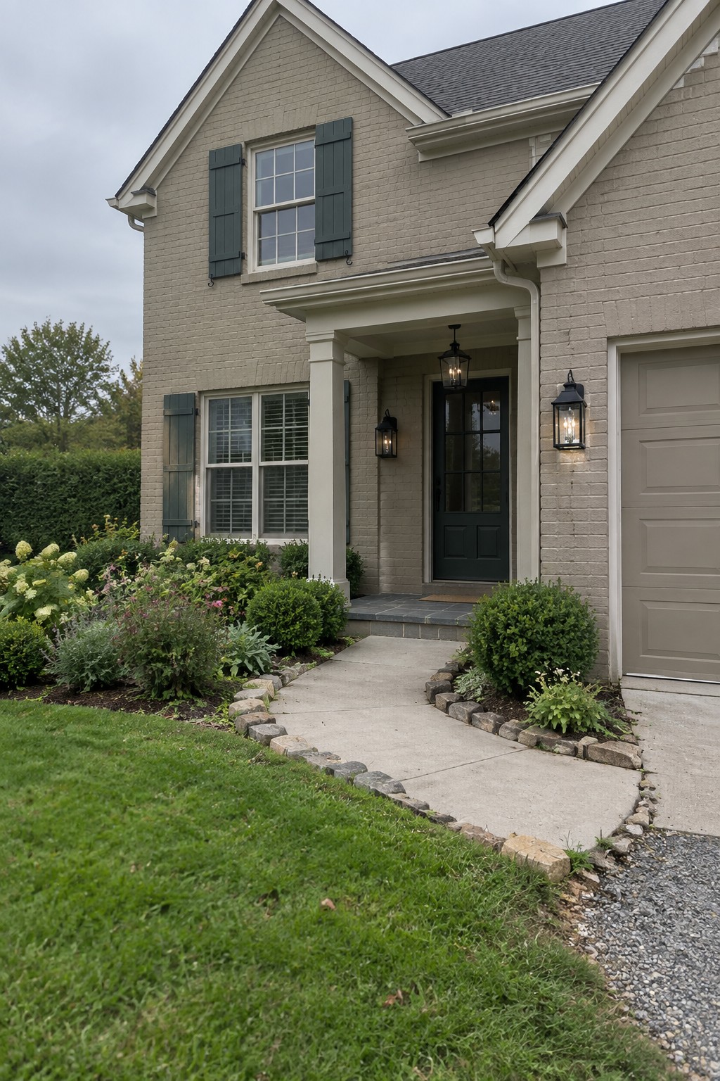 The front of a house painted in a light greige color with a concrete walkway leading to the door.