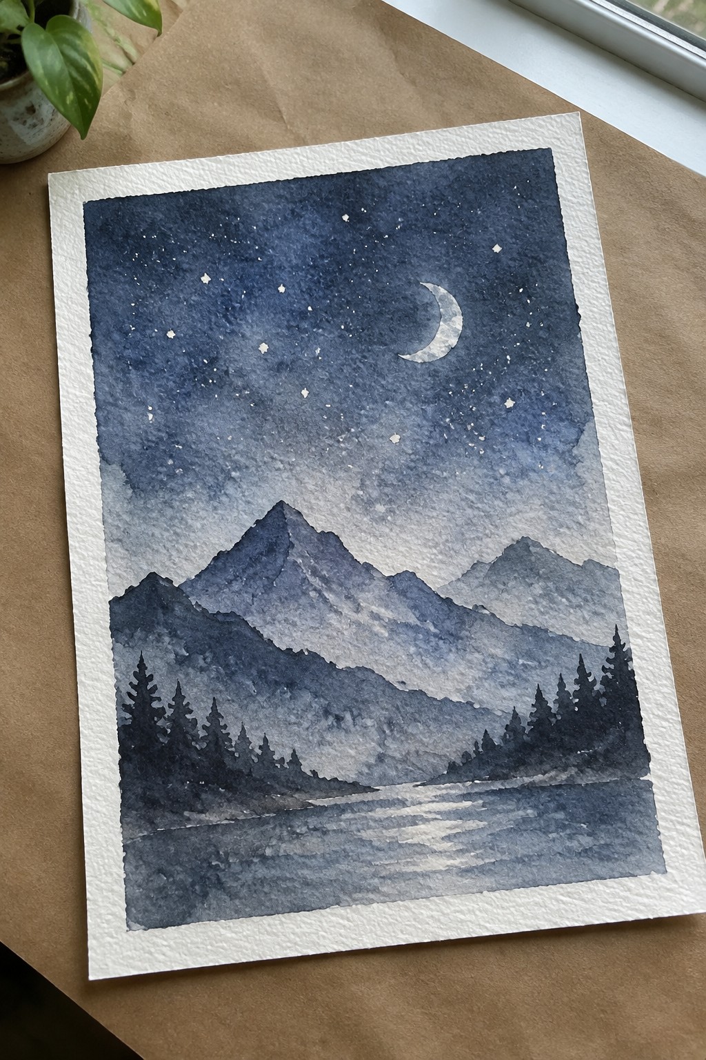 Watercolor night landscape with crescent moon, stars, mountains, pine trees, and reflective water.