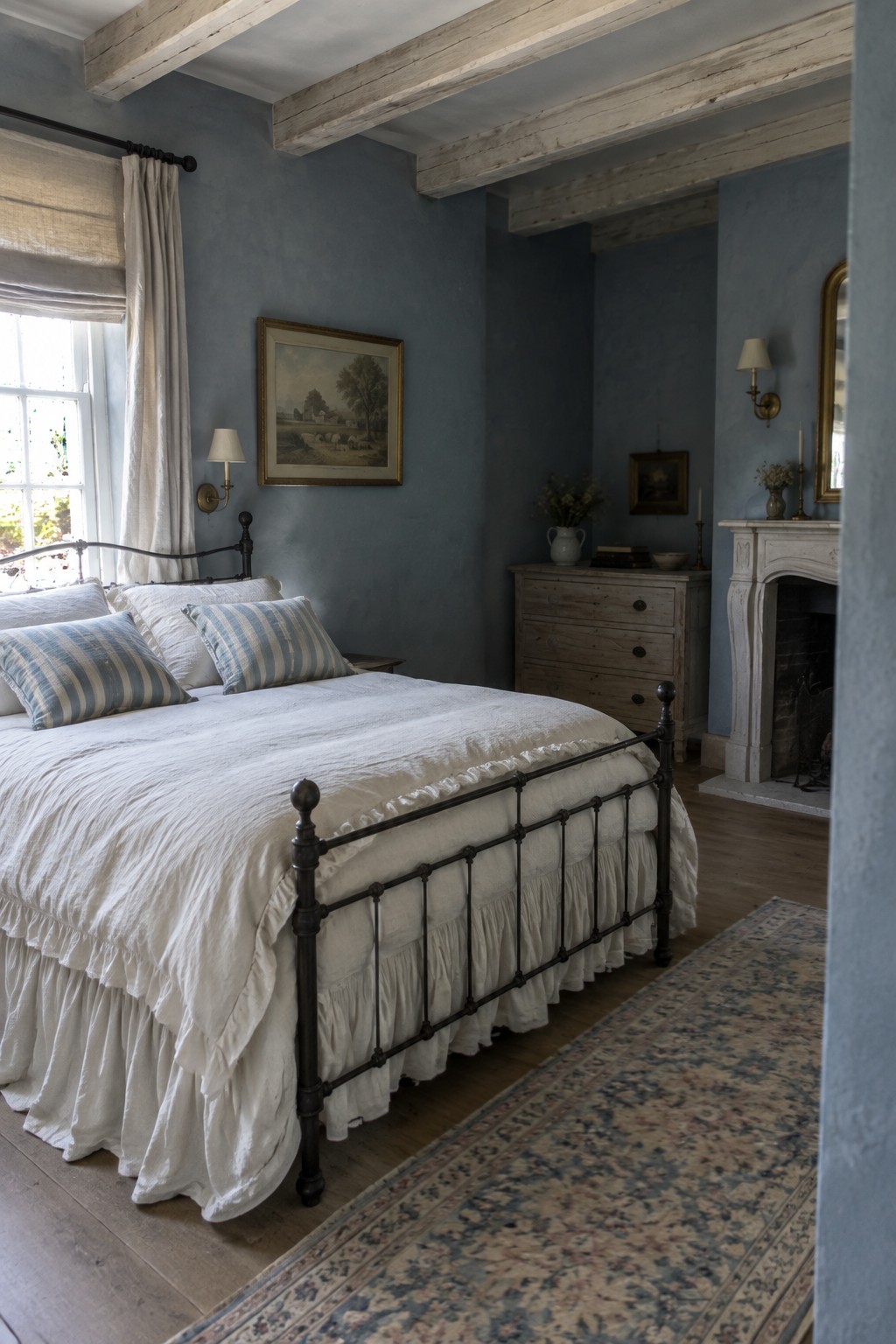 A bedroom with soft blue-gray walls, a black metal bed, and exposed wood beams.