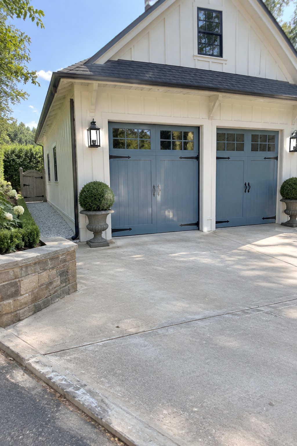 Two soft blue garage doors on a white house with stone accents.
