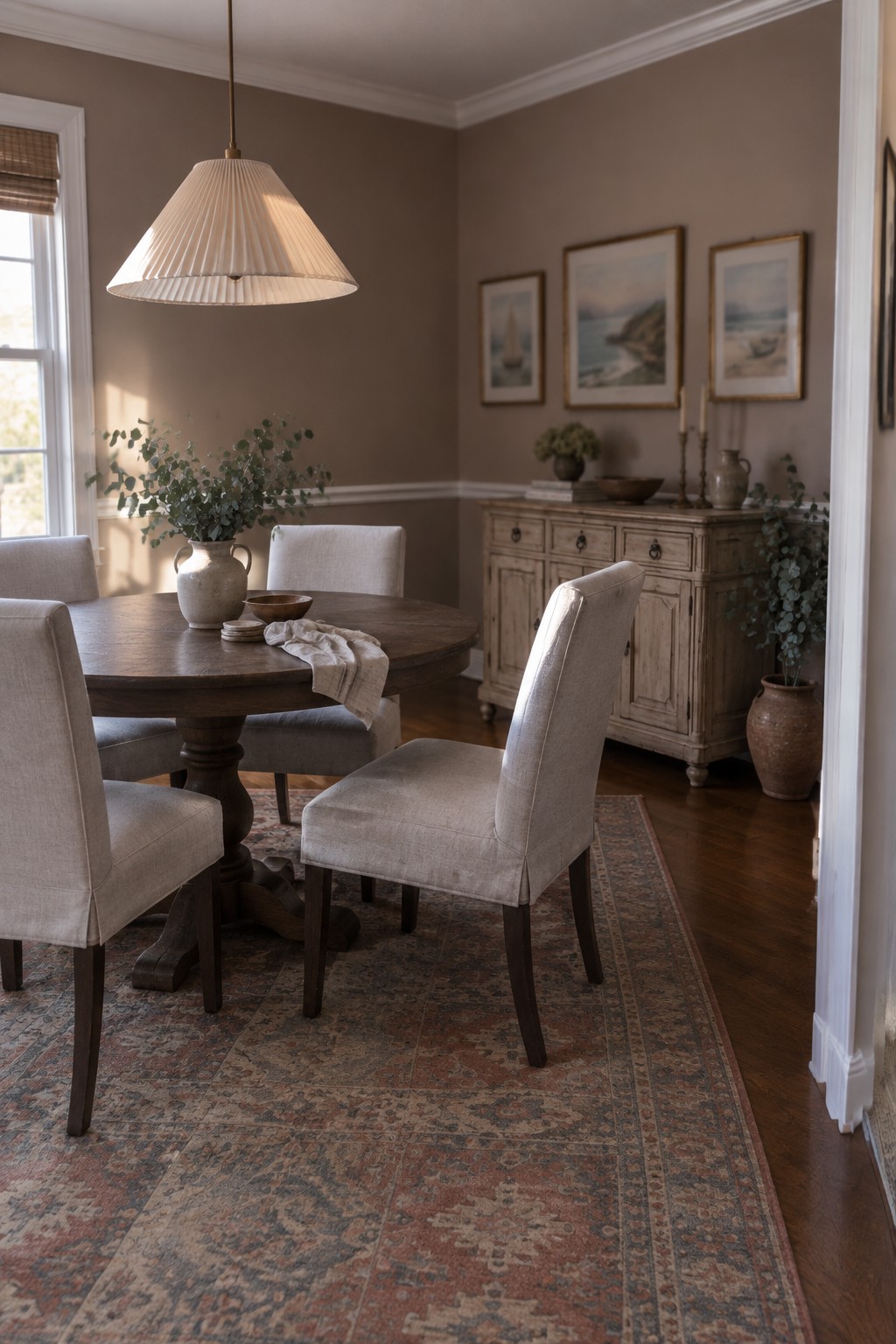 Cozy dining room with round wooden table, beige upholstered chairs, and patterned rug