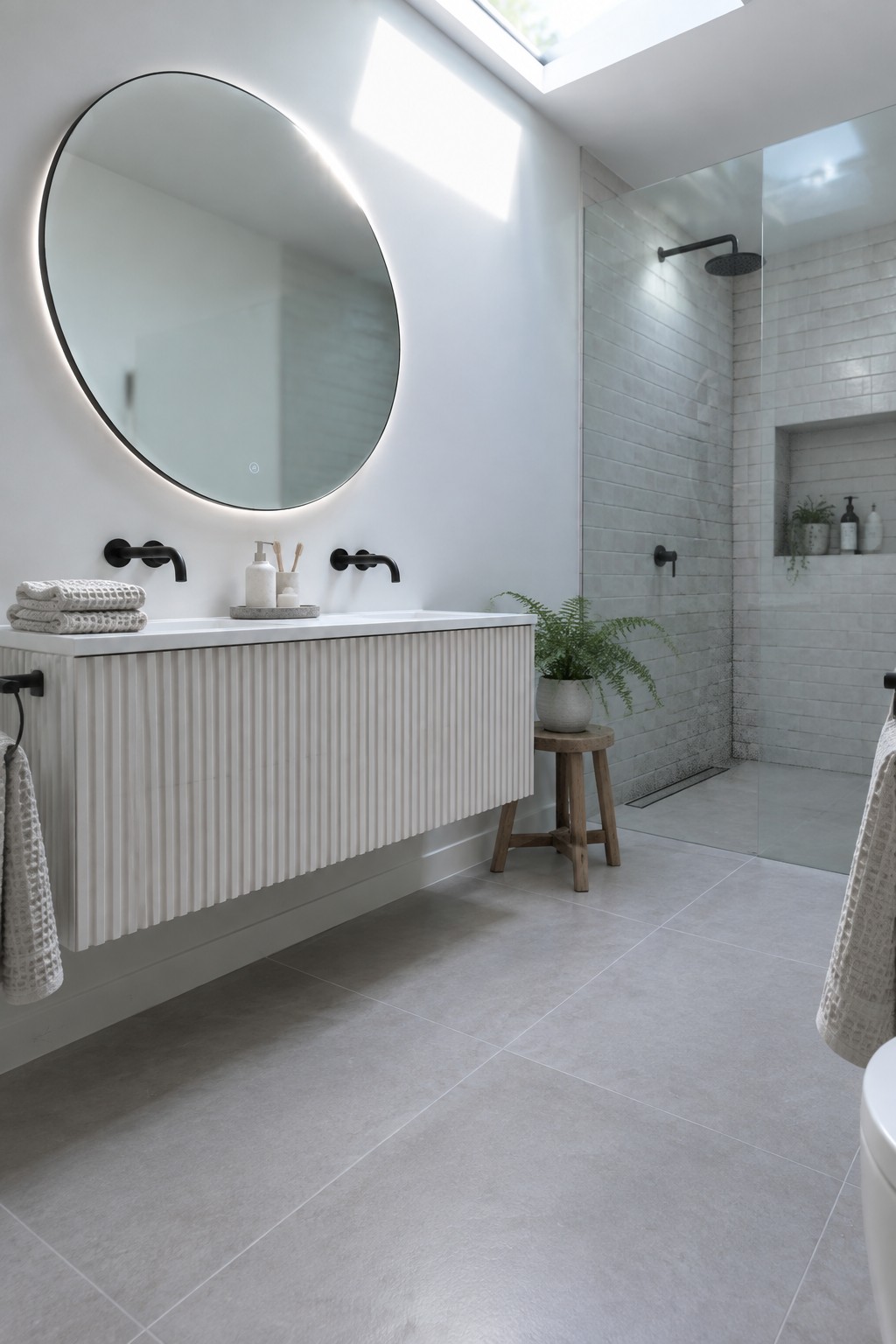 White walls and vanity in a bright modern bathroom with white tile and black fixtures.
