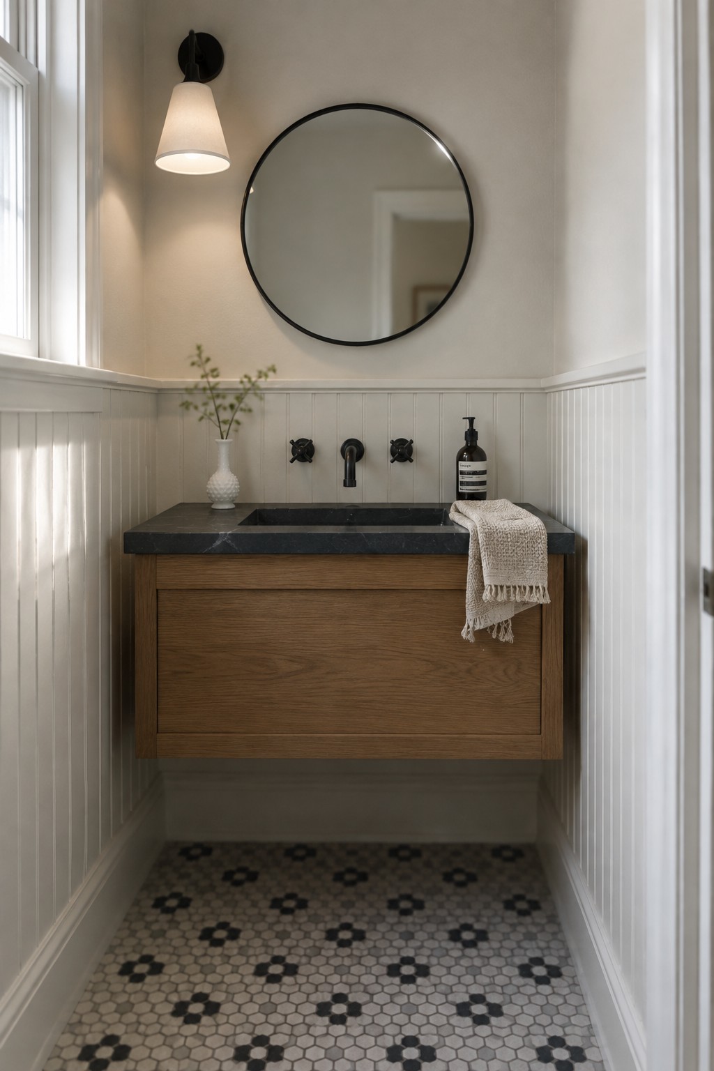 Modern bathroom with floating wood vanity, round black mirror, and patterned tile floor.