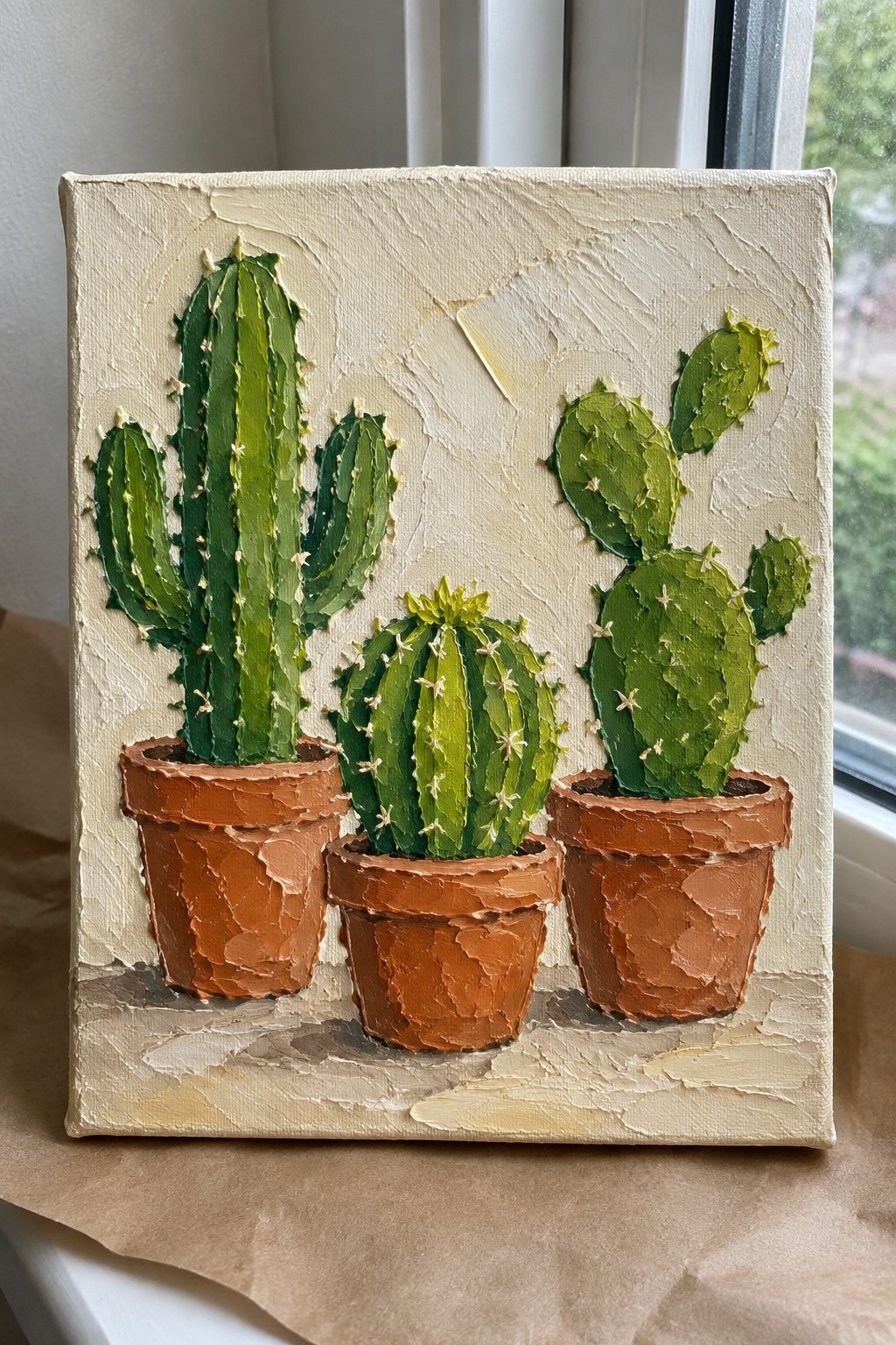 Thick impasto painting of three green cacti in terracotta pots on canvas