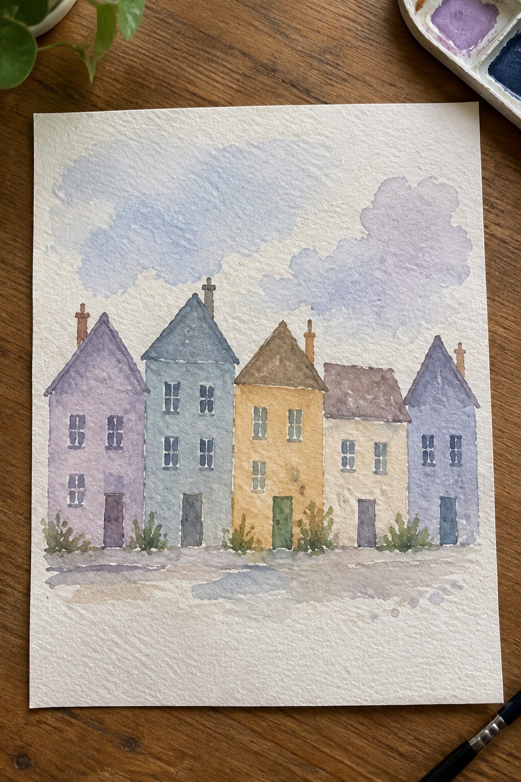 Watercolor of five colorful houses with chimneys under purple-blue clouds and bushes