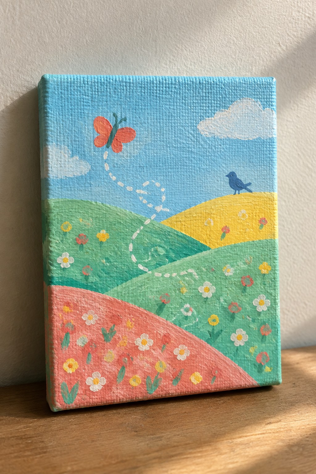 Colorful painting of rolling hills with flowers, red butterfly, blue bird under blue sky