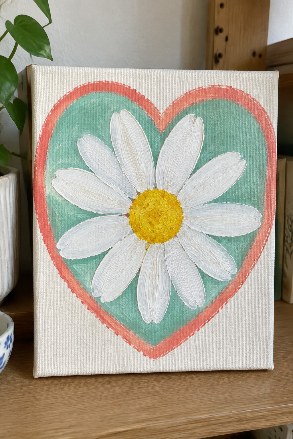 White daisy with yellow center inside coral heart on mint green canvas background