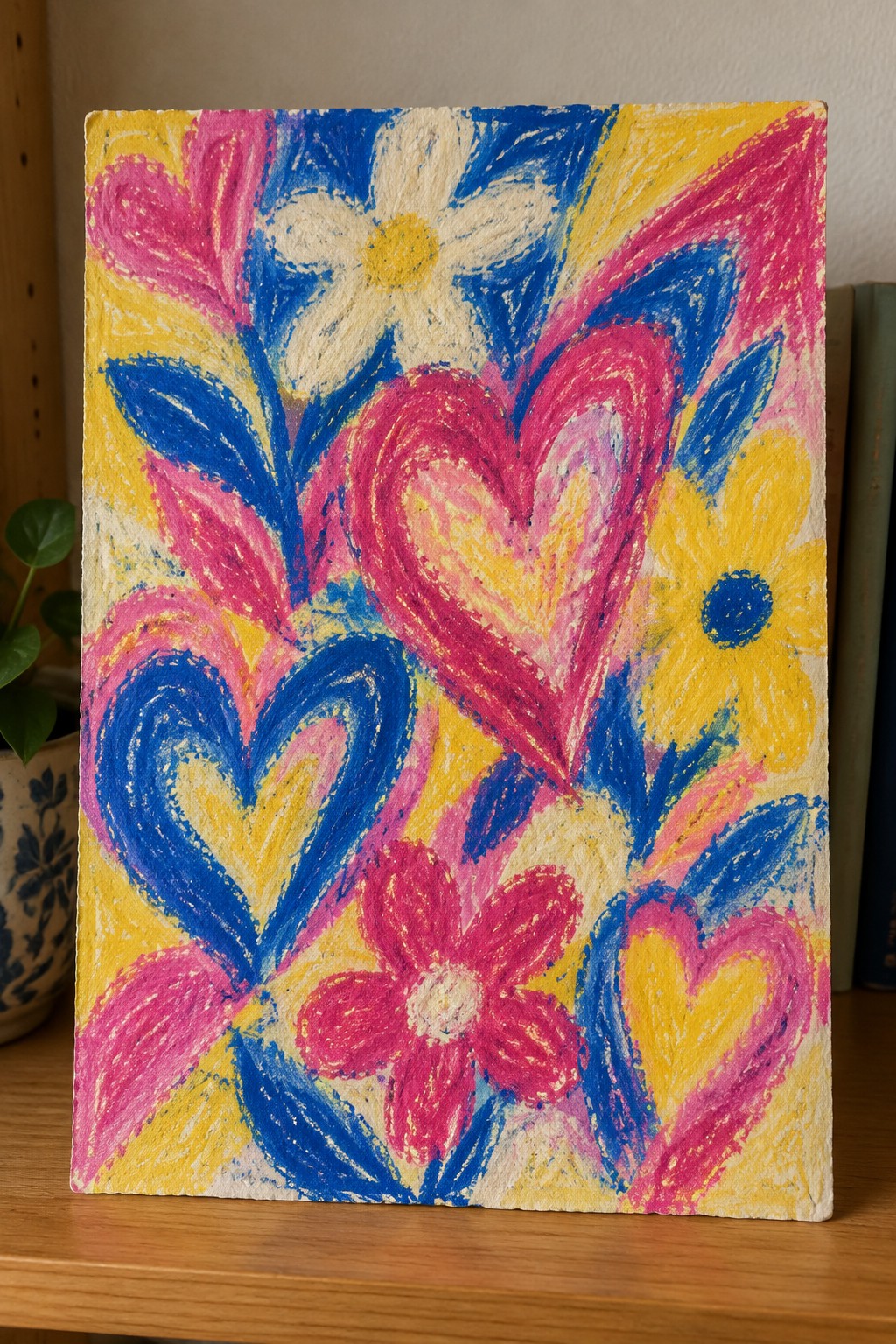 Vibrant painting of pink and blue hearts with yellow and white flowers on wood