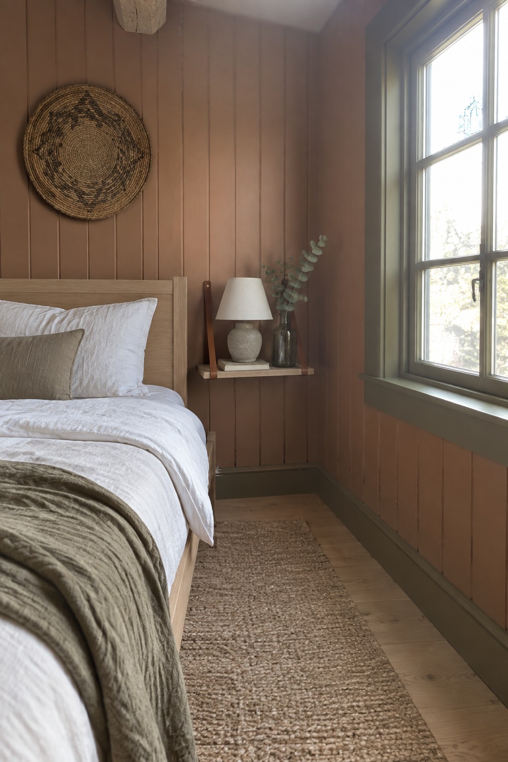 Terracotta painted walls in a bedroom with light wood furniture and natural textures.