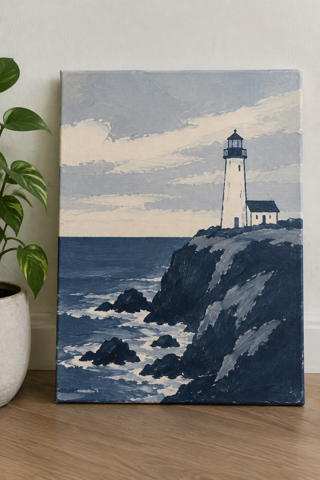 Painting of white lighthouse on rocky cliff above dark blue ocean beside potted plant