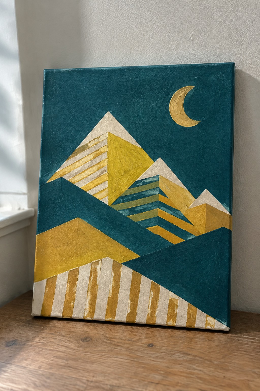 Geometric abstract painting of yellow mountains under crescent moon on teal canvas.