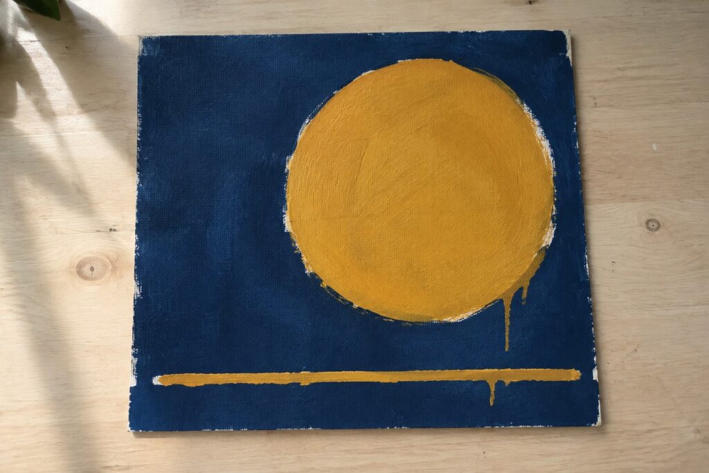 19 Minimalist Painting Ideas for Beginners Using Limited Color Palettes Abstract painting of large yellow circle and dripping line on navy canvas
