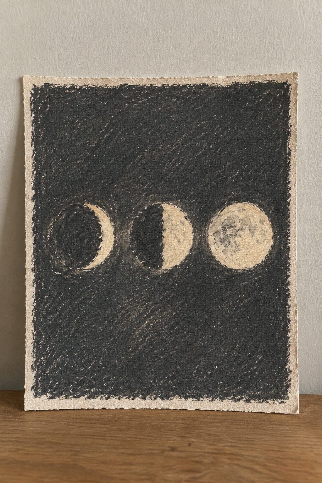 Crescent, half, and full moons in cream on black textured background.