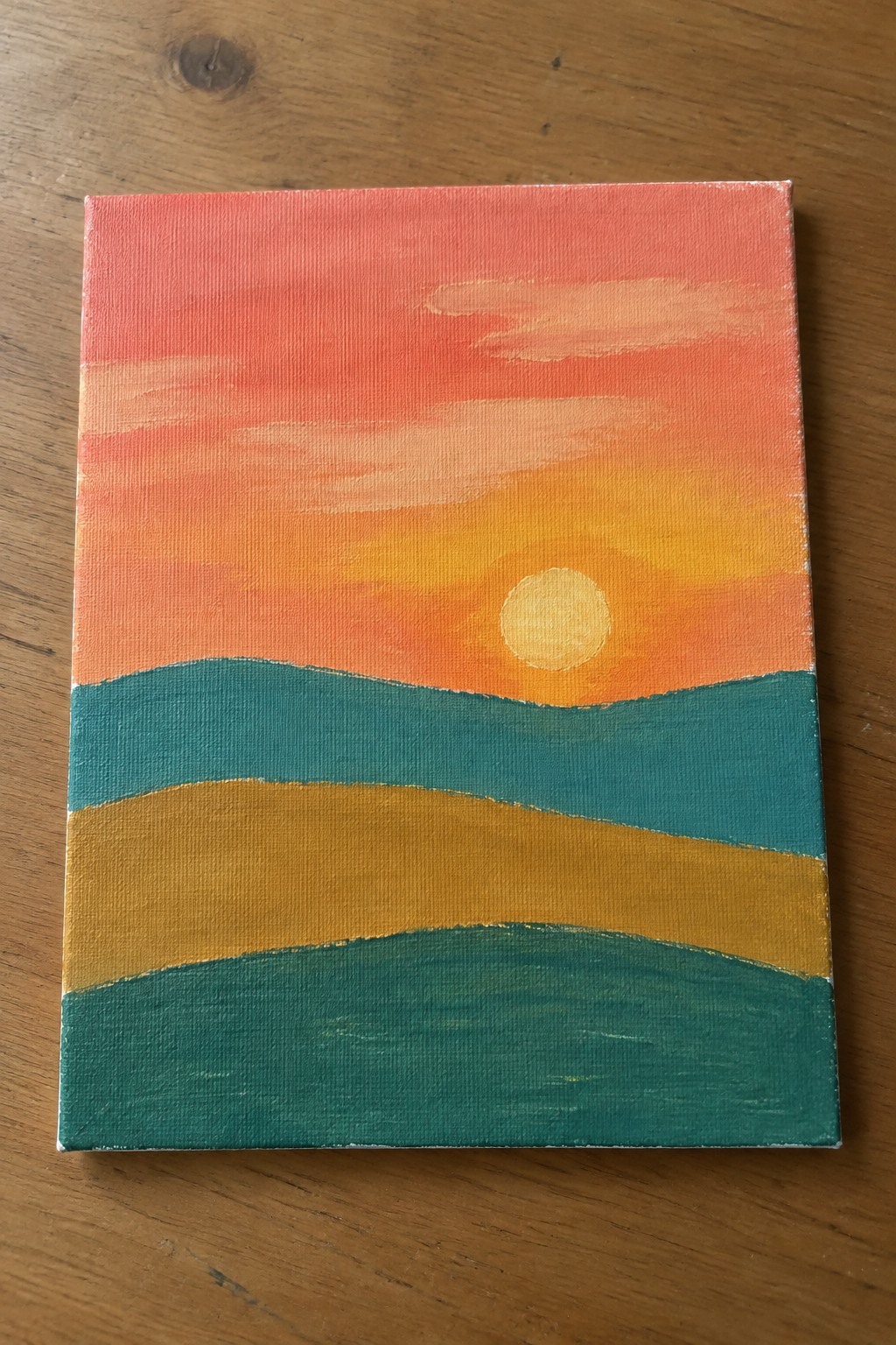 Vibrant canvas painting of sunset with pink-orange sky, yellow sun, teal hills