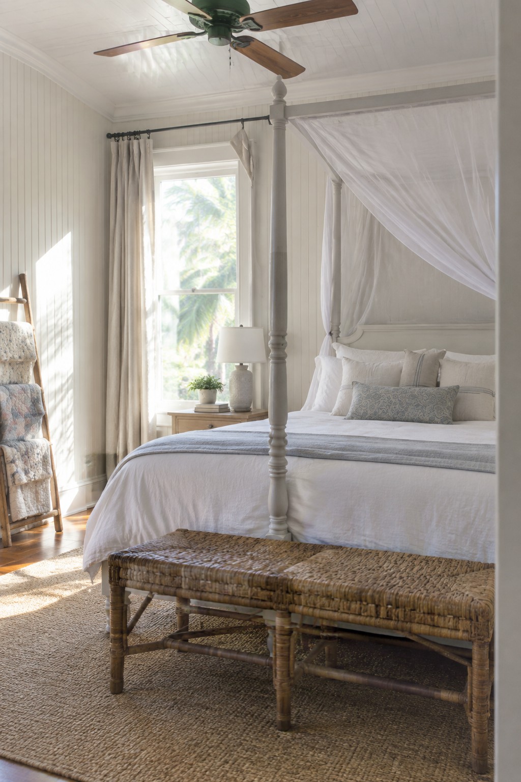 Soft white bedroom walls paired with warm wood flooring and a four-poster bed.