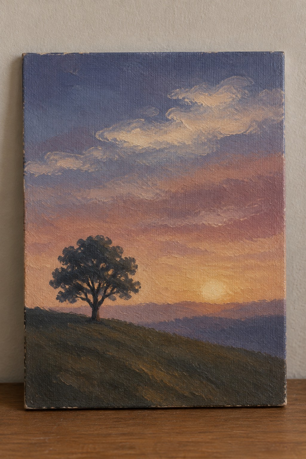 Lone silhouetted tree on grassy hill under vibrant orange-blue sunset sky in oil painting.