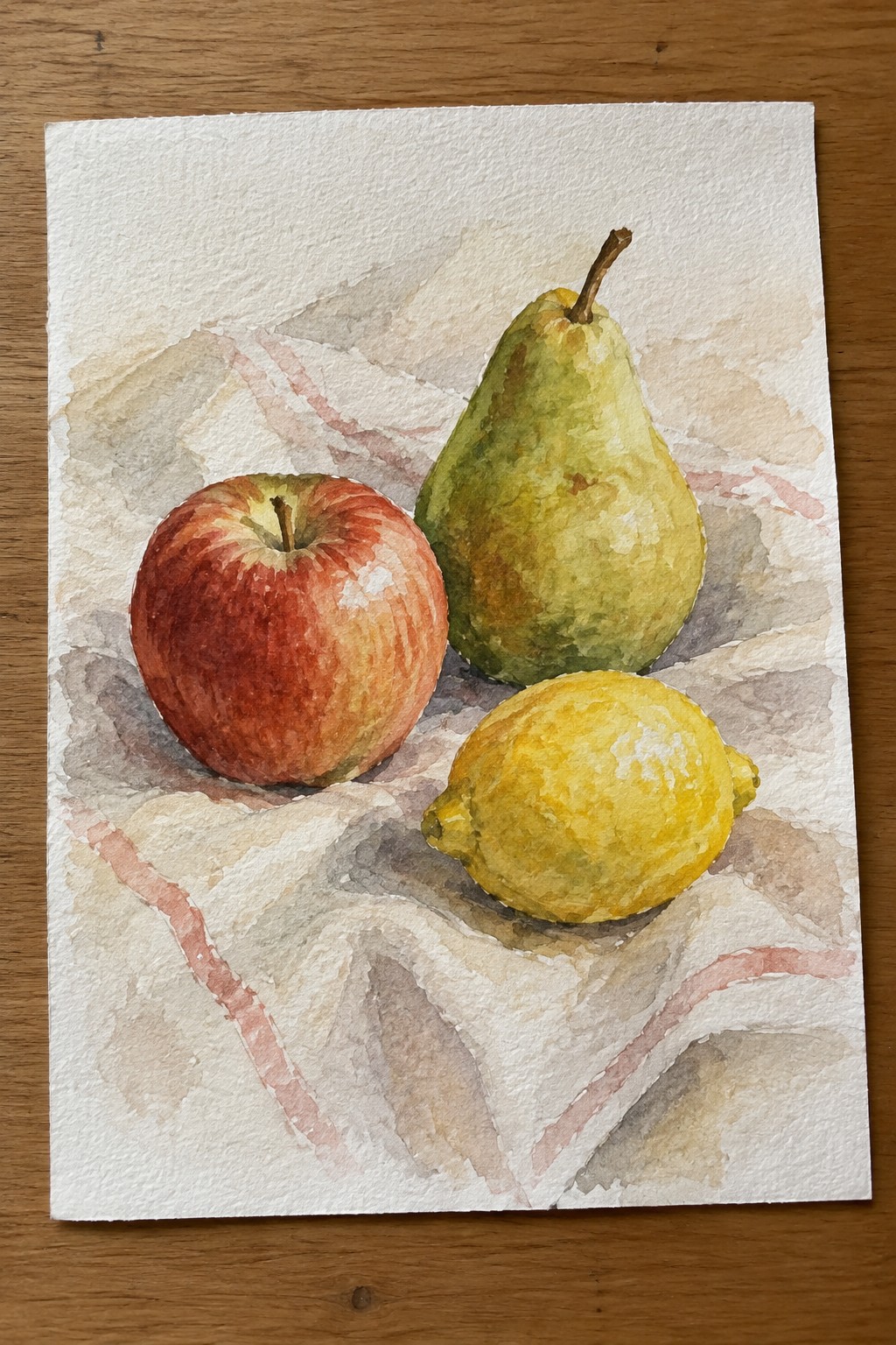 Watercolor still life of red apple, green pear, and yellow lemon on striped cloth.