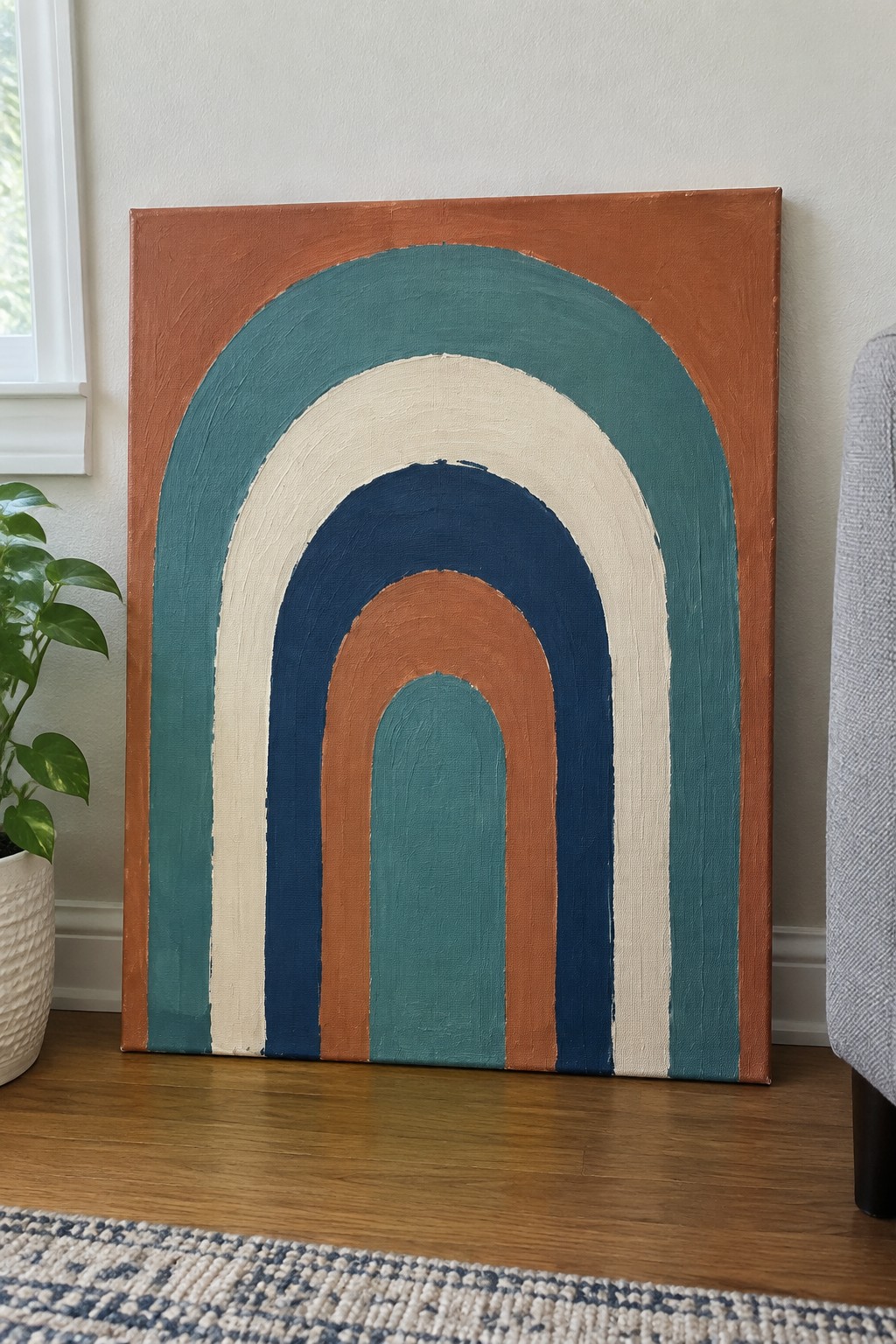 Abstract arched painting in teal, rust, cream and navy leaning on wall