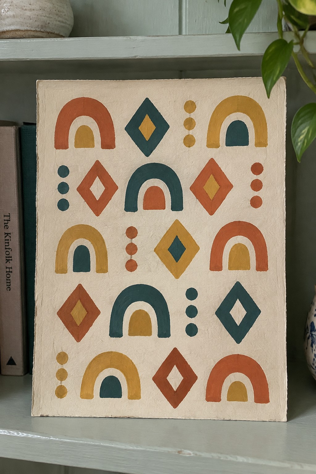 Abstract geometric painting with arches, diamonds, and dots in orange, teal, and yellow on beige canvas