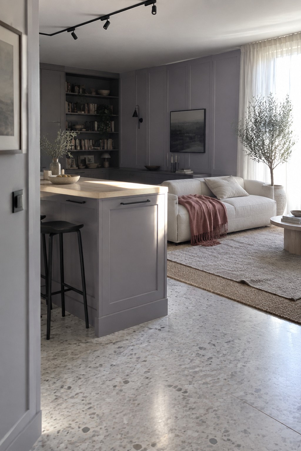 Modern gray kitchen island with bar stool near white sofa on terrazzo floor
