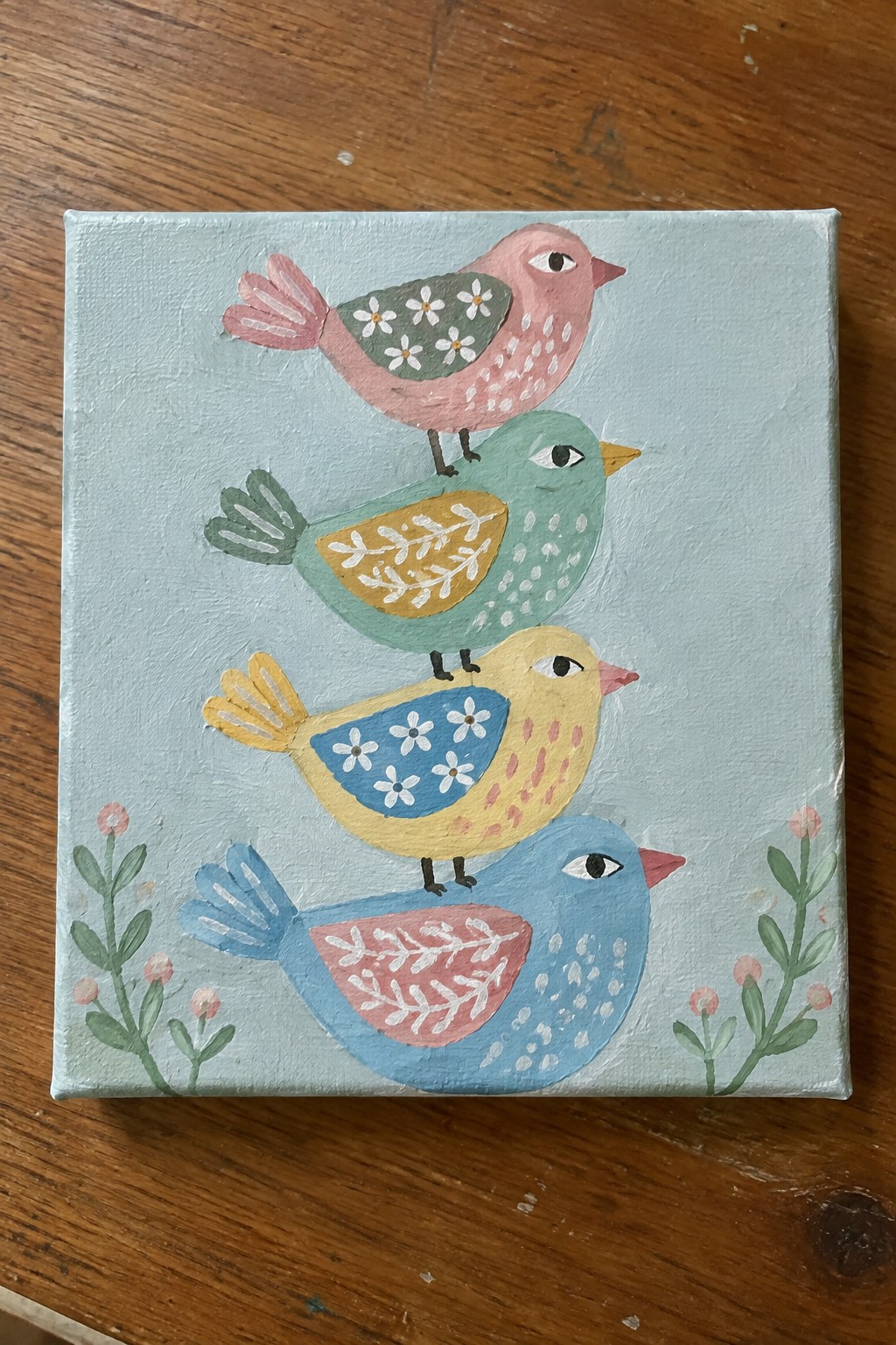 Four stacked colorful birds with patterned wings on light blue canvas