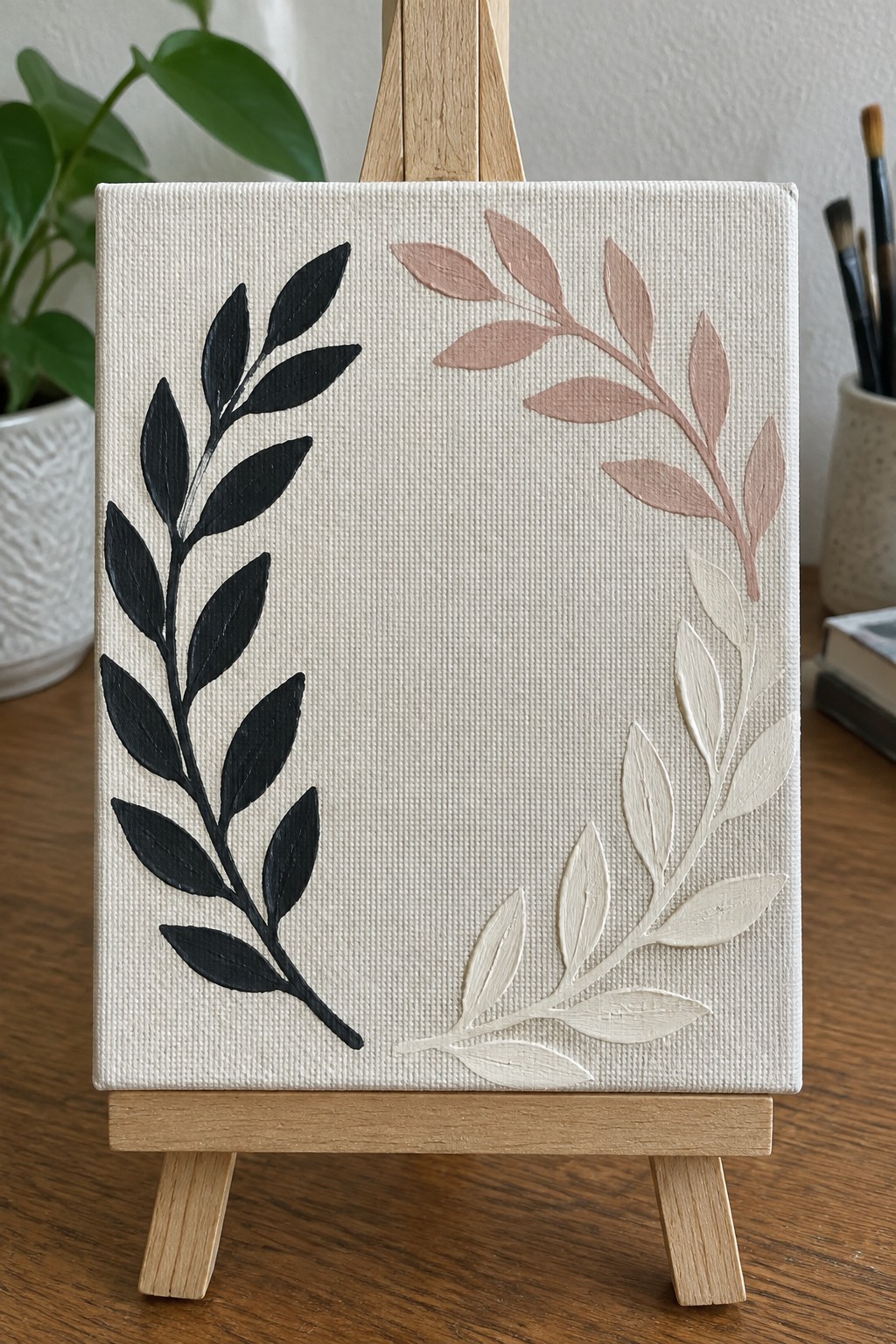 Canvas on easel with black, pink, and white leaf branch paintings