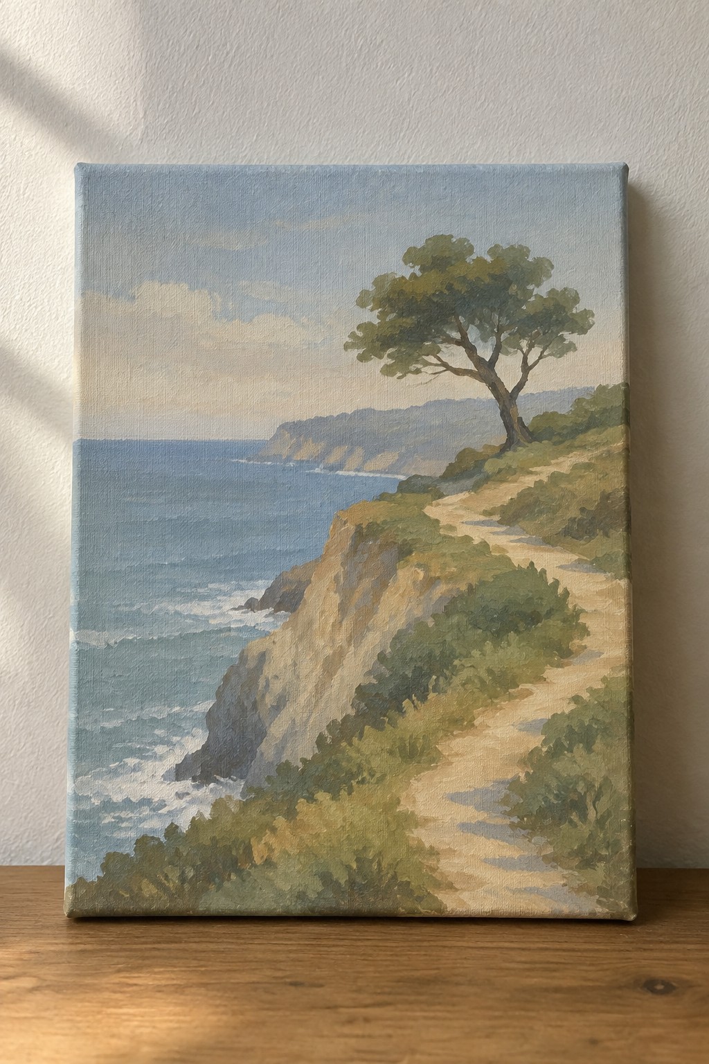 Cliffside dirt path winds past lone tree above blue ocean waves in landscape painting
