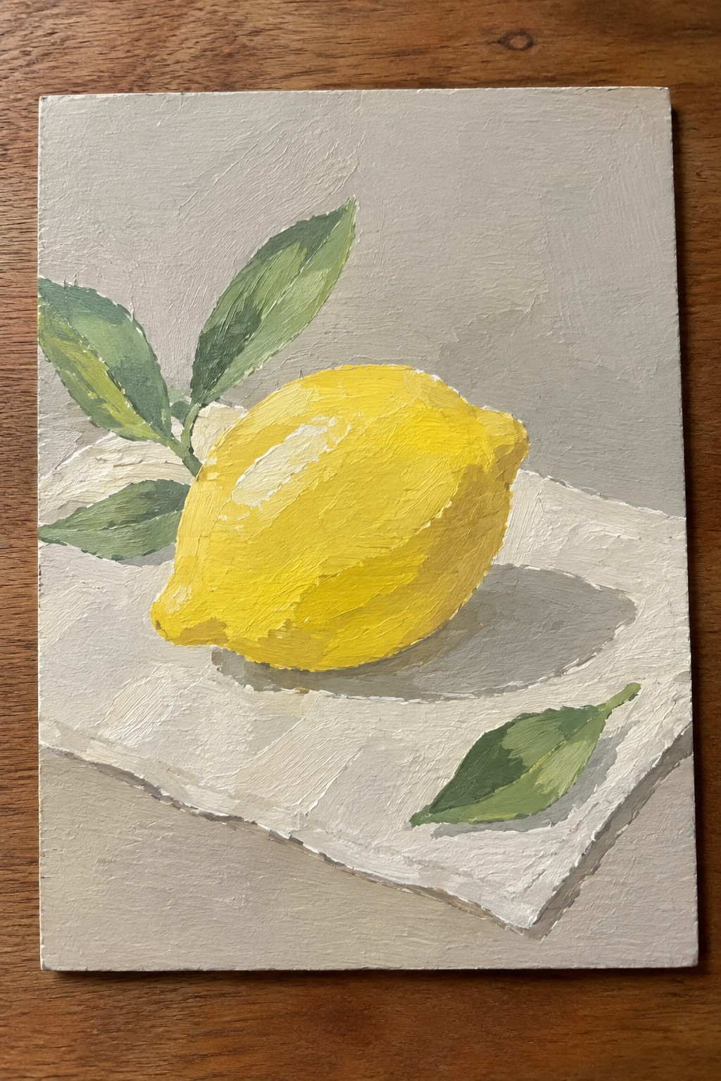 Yellow lemon with green leaves on white cloth against gray background, textured oil painting
