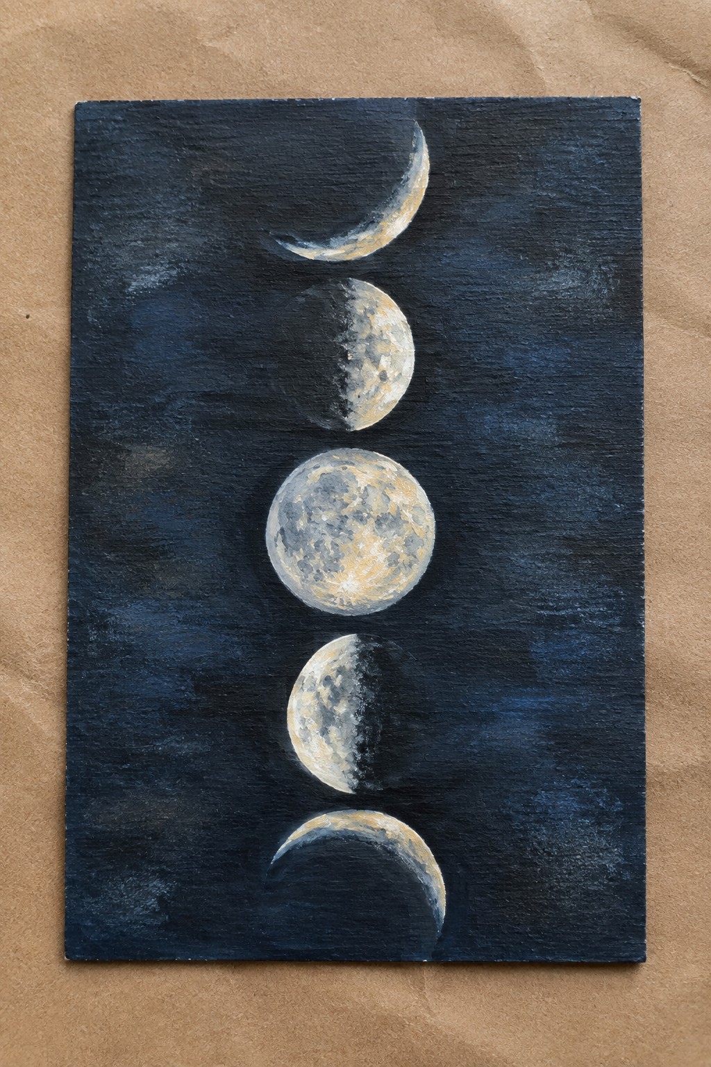Vertical moon phases painted gold and white on textured dark blue canvas.