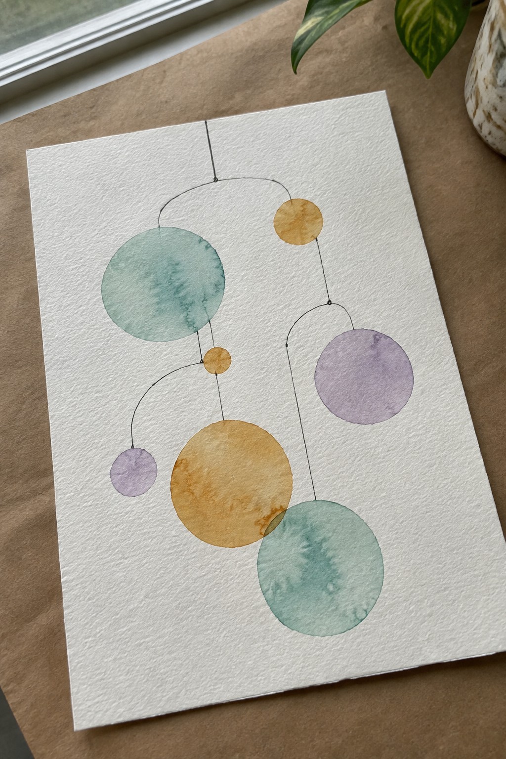 Watercolor painting of abstract mobile with teal, orange, and purple circles on white paper