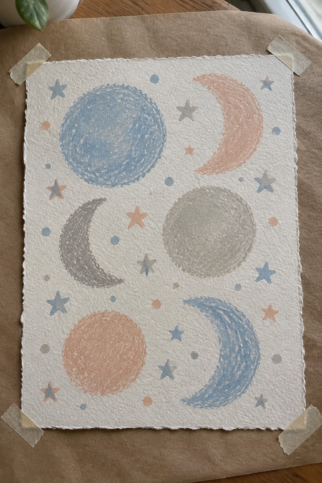 Celestial artwork with moons, stars, and dots in pastel blue and peach on white paper