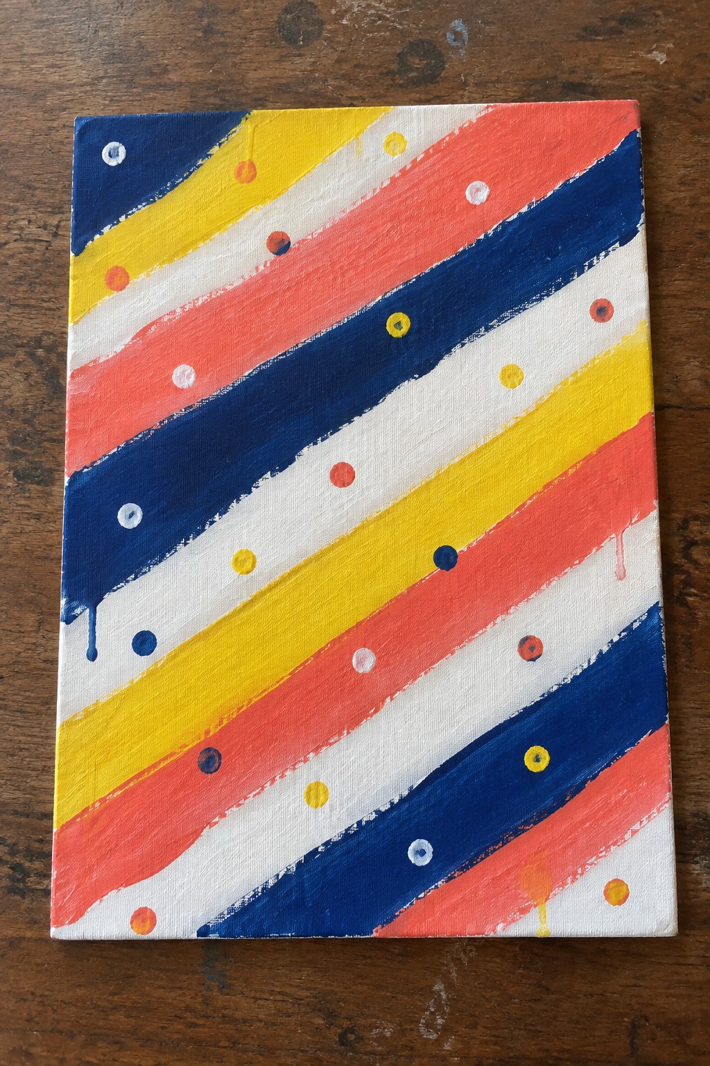 Abstract painting with diagonal stripes in blue, yellow, red and white, accented by colorful dots and drips.