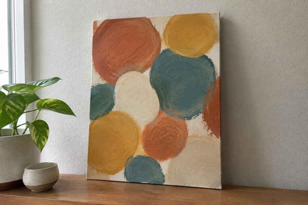 21 Easy Abstract Painting Ideas Using Simple Shapes Abstract painting of overlapping circles in orange, yellow, teal on wooden shelf