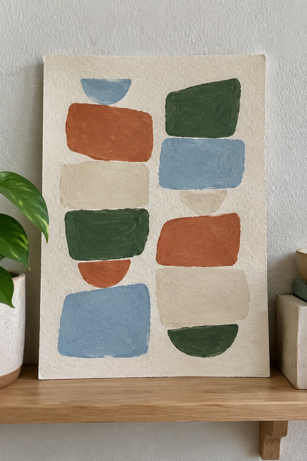 Abstract painting with colorful rounded shapes in blue, orange, green, and beige on shelf