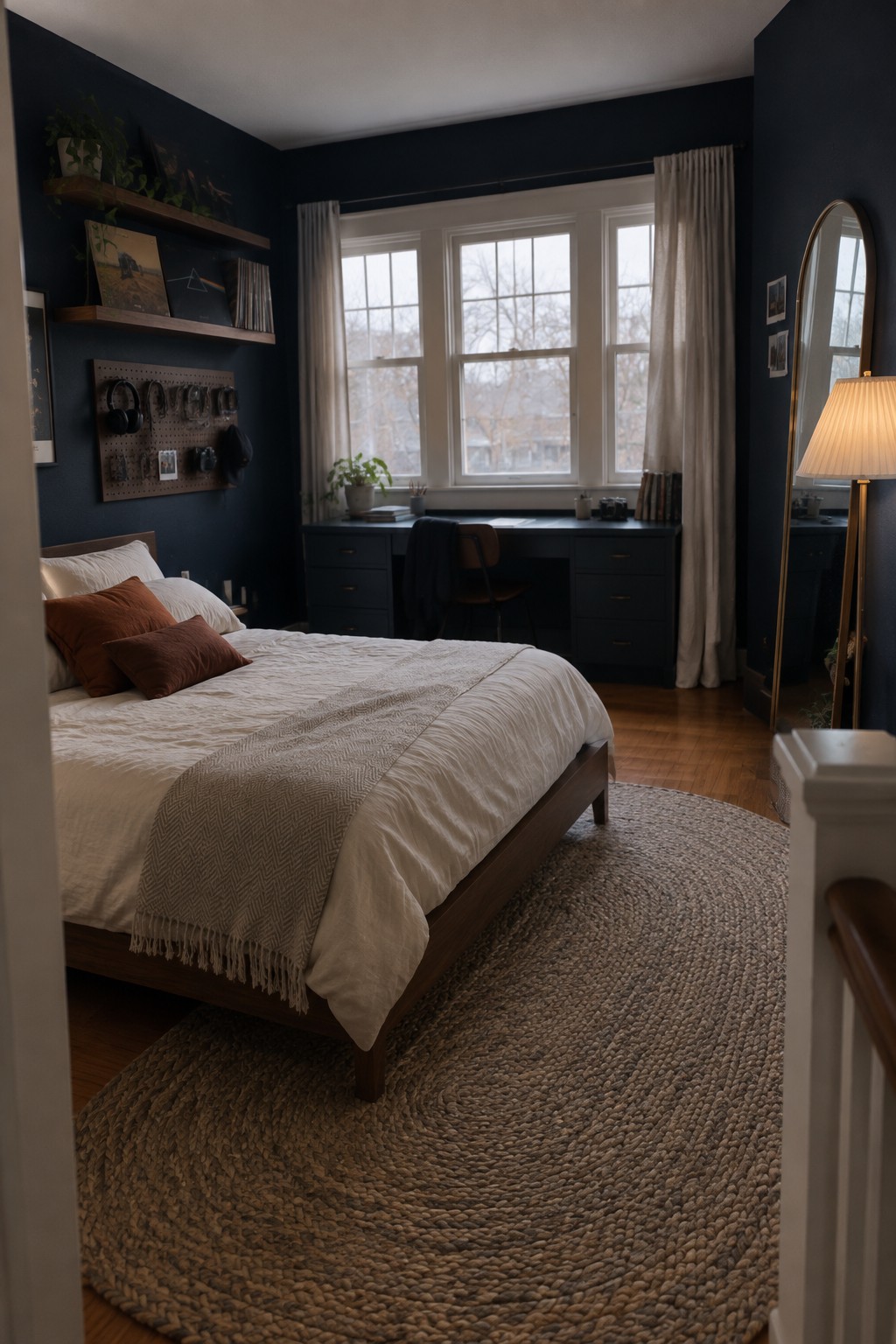 A teen bedroom with deep navy walls, a wooden bed frame, and a large window area.