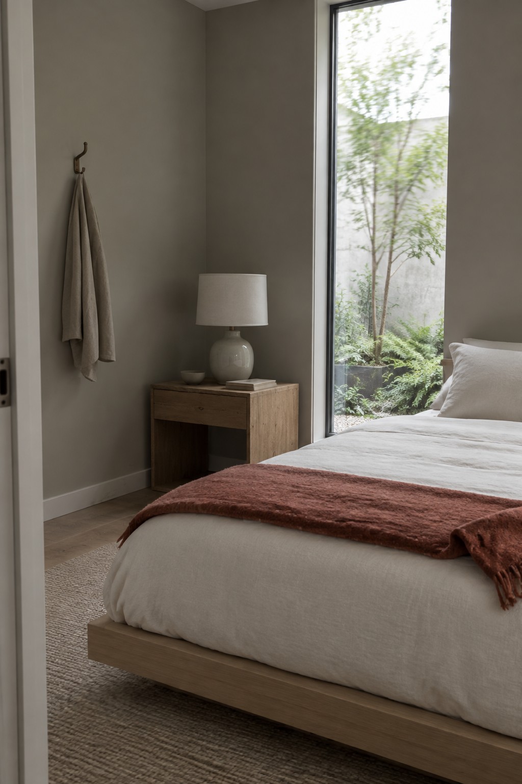 A bedroom with warm greige walls and light wood furniture.