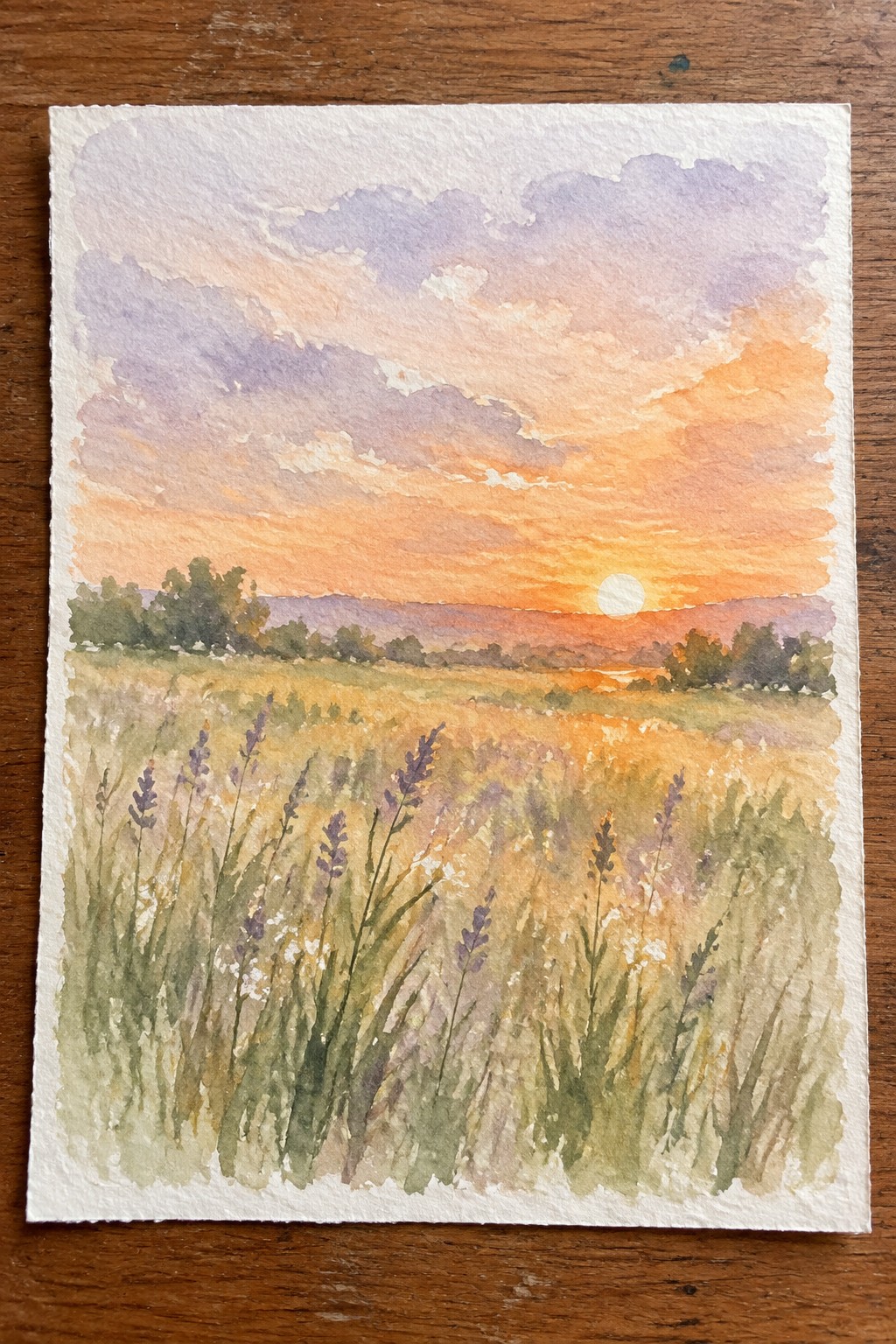 Watercolor sunset over wildflower meadow with purple blooms, orange sky, hills and trees