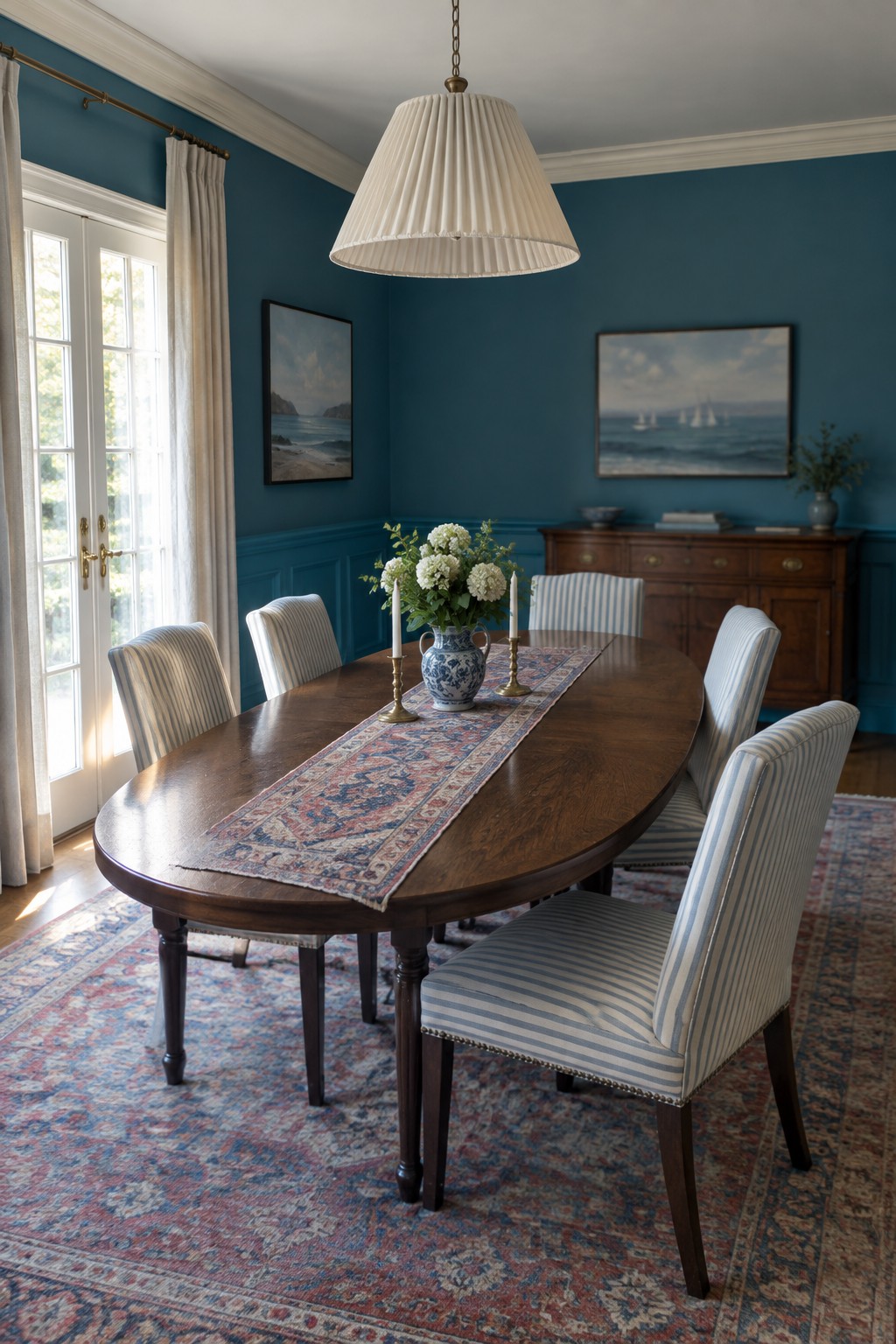 A dining room with deep blue walls and matching wainscoting around a dark wood table.