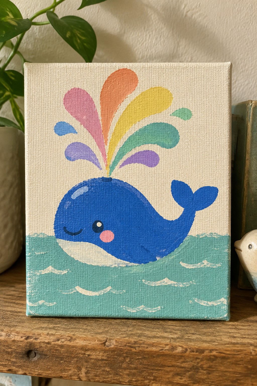 Cute blue whale with rainbow spout swimming in teal waves on canvas