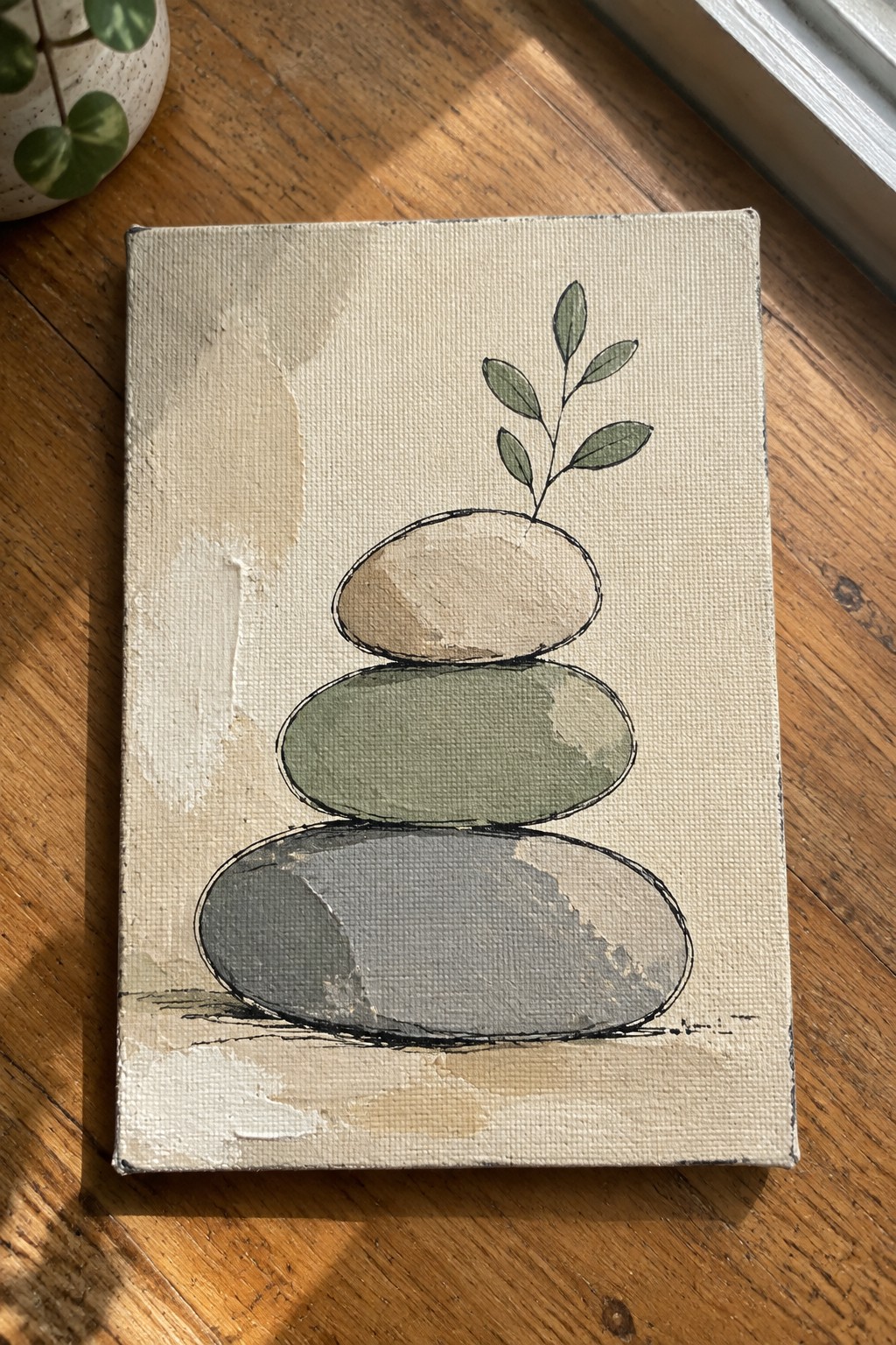 Painting of stacked gray green and beige stones with leafy branch on canvas.