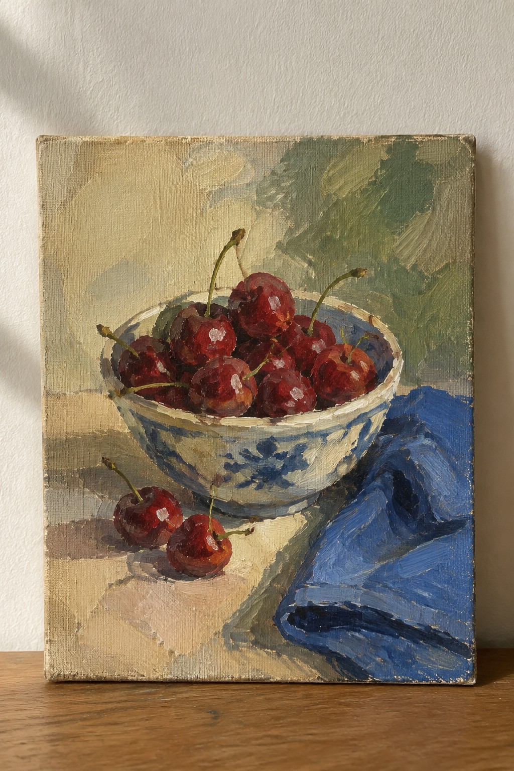Red cherries in blue-and-white bowl beside blue cloth, loose brushstrokes