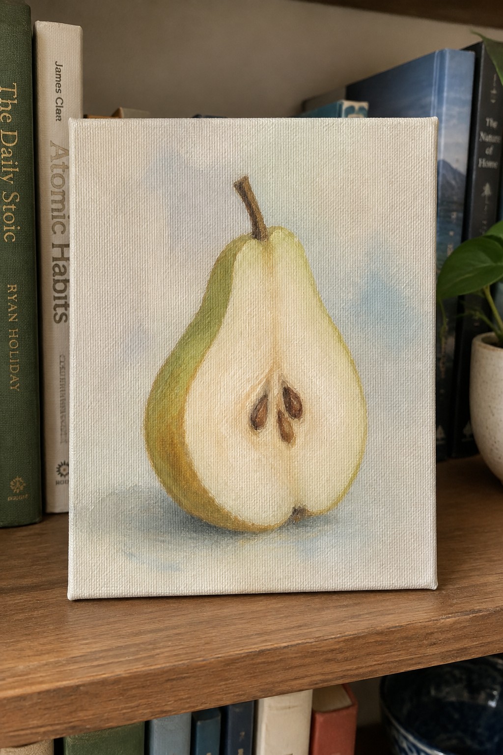 Oil painting of sliced pear on canvas atop wooden bookshelf with books