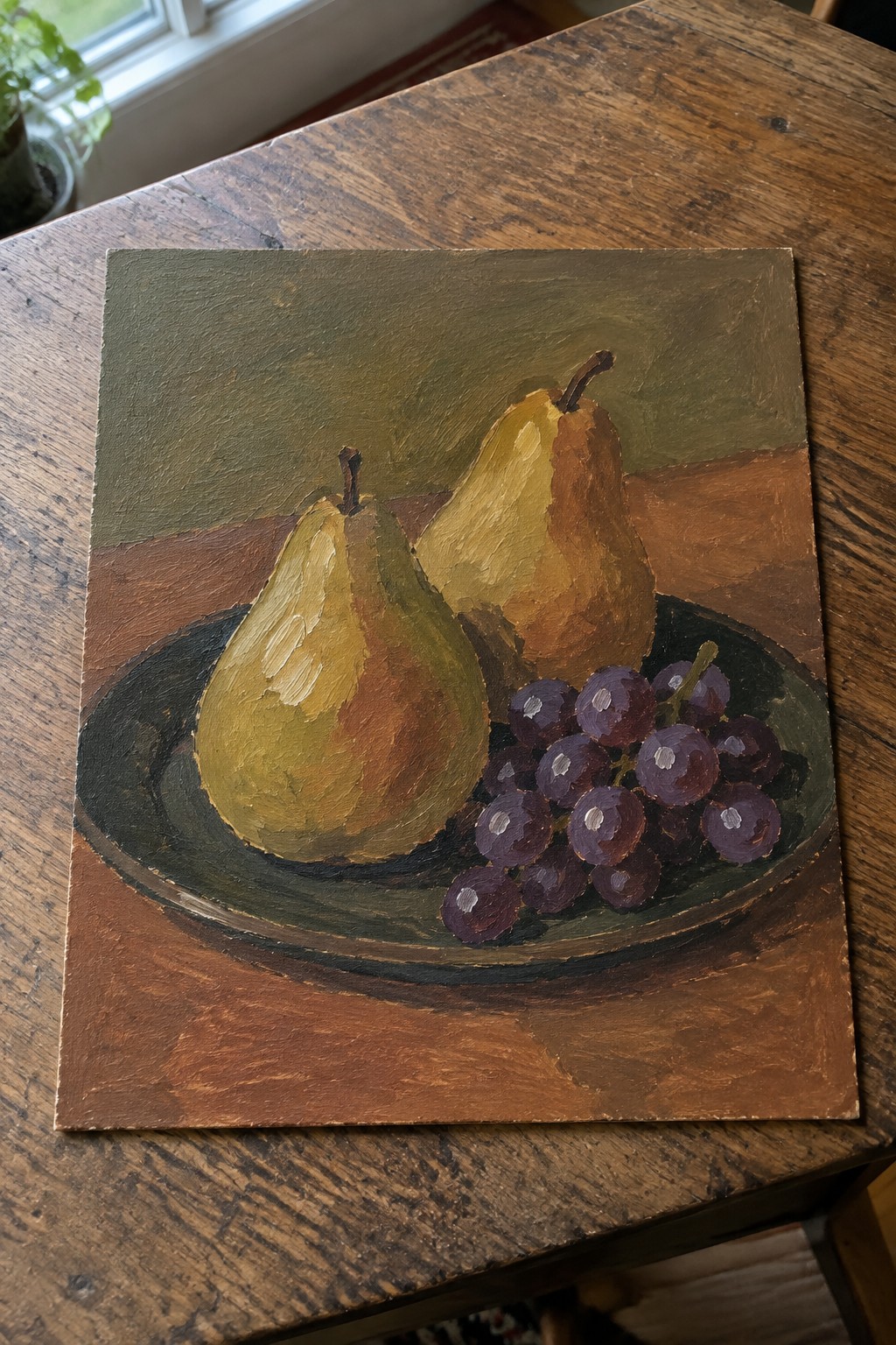 Oil still life of two pears and purple grapes on dark plate atop wood