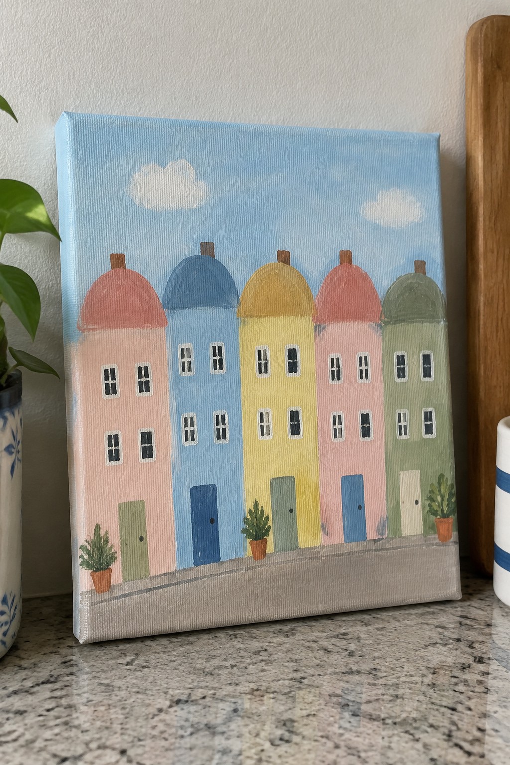 Pastel domed houses in pink, blue, yellow, and green on canvas.